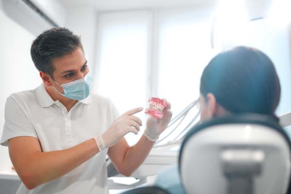 young,dentist,in,white,uniform,and,protective,medical,mask,showing